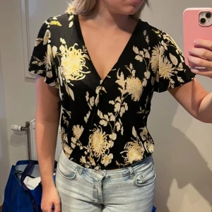 Svart blommig omlottopp - Snygg svart omlottopp med blommor från Gina tricot. Fint skick, storlek S 🌸 