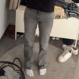 Grå jeansbyxor - Säljer ett par grå jeansbyxor med en klassisk straight passform. Byxorna har en enkel design med fem fickor och en knappgylf. Perfekta för en avslappnad stil. Det är ett litet hål på ena fickan men går att sy, och även lite slitage vid fötterna