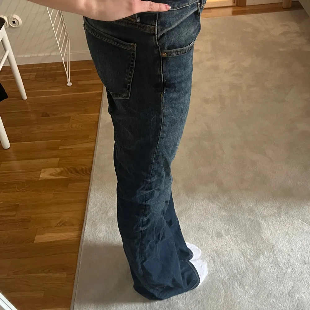 Säljer ett par klassiska blå bootcut jeans med normal passform och låg midja. Jeansen har fem fickor, dragkedja och knapp framtill. Perfekta för dig som gillar en tidlös denimstil.. Farkut & Housut.