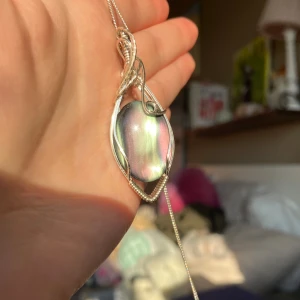 Halsband med silverinfattad regnbågsskimrande sten. Reserverad!✨ - Unikt halsband med en oval, regnbågsskimrande sten infattad i en dekorativ silverram. Berlocken är reserverad!✨