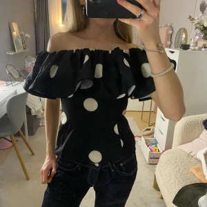 Svart offshoulder topp med vita prickar - Säljer en snygg svart offshoulder topp med vita prickar, helt ny med prislapp kvar 