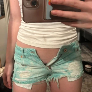 Turkosa jeansshorts från Pull&Bear - Turkos och vit blandade slitna shorts från pull&bear. Låg midja. Se sista bilden för midjemått. 