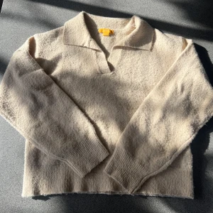 Beige stickad tröja med krage - Mysig beige stickad tröja med krage och långa ärmar. Perfekt för sena sommardagar med sin mjuka och bekväma design. Ribbstickade muddar vid slutet av ärmarna och nederkant ger en fin passform. Inga defekter och är köpt från Gina Young💗