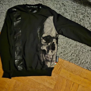 Philipp Plein  - Svart sweatshirt från Philipp Plein med "plajett" dödskalle tryck och Philipp plein text detalj längs ena sidan. Oanvänd och i nyskick ännu har enbarts körts i tvättmaskin 1 gång p.g.a jag är allegisk mot medlena i nya kläder, men den är Oanvänd och i nyskick ännu. Kommer i Storlek L/Large  säljs för 1500 kr. Vid snabb affär 1000. Finns i Gränna att hämtas. OBS OBS OBS Vid frakt av tröjan står ni för porto kostnade själva!