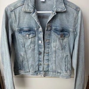 Ljusblå jeansjacka från H&M - Snygg ljusblå jeansjacka från H&M i storlek 38. Jackan har en klassisk design med knappar framtill och fickor både på ut-och insidan. Perfekt för vår och sommar! ☀️🩵