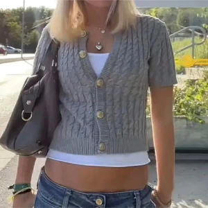 Grå ribbad kofta med korta ärmar - Snygg grå kofta med korta ärmar och ribbad struktur. Den har dekorativa knappar framtill och en rund halsringning. 