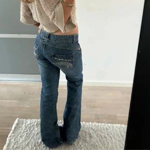 Blå bootcut jeans med detaljer - Snygga blå lågmidjade jeans med snygga fickor. Köpta här på Plick men tyvärr lite för små för mig. Midjemåttet är ca 36 cm rakt över och innerbenslängden 82. Bilderna är från förra säljaren men kan absolut skicka egna!💕