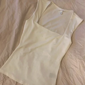 Vit ärmlös topp från H&M - Säljer en stilren vit ärmlös topp från H&M. Perfekt för varma dagar. Toppen har en enkel och elegant design med en rundad halslinje. Aldrig använd!!