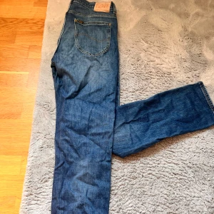 Blå jeans från Lee - Säljer ett par klassiska blå jeans från Lee. De har en normal passform och är tillverkade i slitstarkt denim. Perfekta för en avslappnad stil.