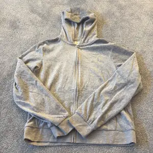 Säljer en stilren grå huvtröja med dragkedja och huva från Juicy couture. Tröjan har ett dekorativt mönster med paljetter på bröstet och ryggen. Perfekt för en avslappnad stil. Inte använd. 