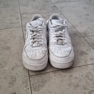 Vita Nike Air Force sneakers - Säljer ett par klassiska vita Nike Air Force sneakers. De har en rund tå och snörning framtill. Perfekta för en stilren look.