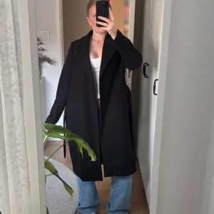 Svart kappa - Säljer en svart lång kappa från Veromoda. Jackan har en rak passform och perfekt för en stilren look. Lite kopprig men annars i fint skick.