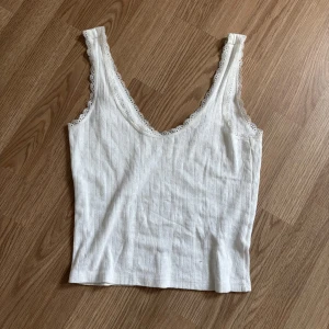 Vintage linne monki  - Säljer en vit ribbad linnetopp med djup v-ringning och fina spetsdetaljer längs kanterna. Perfekt att styla till jeans eller kjol för en fräsch look. Från monki. Använd en gång. Storlek S🤍