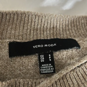 Beige stickad tröja från Vero Moda - Mysig beige stickad tröja från Vero Moda. Tröjan har rund halsringning, långa ärmar och ribbade muddar vid ärmslut och nederkant. Perfekt för lager-på-lager och enkel att matcha med jeans eller kjol.