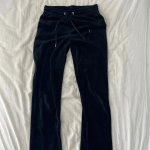 Lågmidjade Svarta mjukisbyxor i velour - Säljer ett par svarta mjukisbyxor i mjuk velour med resår och silkesknyt i midjan. Byxorna har lätt utsvängda ben och en avslappnad passform. Kan kombineras med tröjan i samma set för 250, pris kan diskuteras🥰 