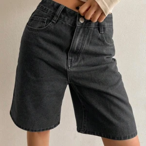 Svarta jeansshorts  - Snygga svarta jeansshorts med klassisk femficksdesign och knappgylf. Modellen har en rak och lite längre passform som slutar ovanför knäna. Perfekta för en avslappnad stil och enkla att matcha med olika toppar.Stl M men passar s