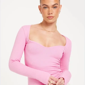 Rosa långärmad topp  - Snygg rosa topp med lång ärm och sweetheart ringning. Ribbat material ger en snygg och bekväm passform. Perfekt att styla till jeans eller kjol.