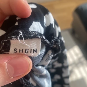 Svart kjol med hjärtmönster från Shein - Söt svart kjol från Shein med vita hjärtan över hela tyget. Kjolen har en bekväm resår i midjan och är perfekt för en lekfull stil. Den är gjord i ett lätt och luftigt material som passar bra till varmare dagar.