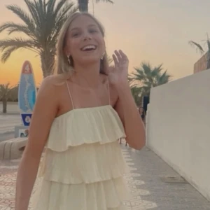 Ljusgul axelbandslös klänning - Charmig ljusgul klänning med volanger i flera lager. Axelbandslös design som ger en luftig och somrig känsla. Perfekt för varma dagar och festliga tillfällen.