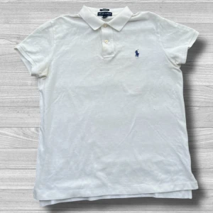 Ralph Lauren piké - Säljer en klassisk vit pikétröja från Ralph Lauren i storlek M. Tröjan har korta ärmar och en broderad blå logotyp på bröstet. Perfekt för en stilren och avslappnad look.