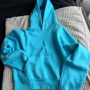 Turkos oversize cropped hoodie från Zara  - Säljer en snygg turkos oversize cropped hoodie med en stor och bekväm huva. Tröjan har en klassisk känguruficka framtill och är perfekt för en avslappnad stil. Passar bra till både jeans och mjukisbyxor.