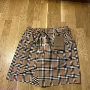 Rutig shorts från Burberry - Snygga rutiga shorts från Burberry i klassiskt mönster. De har en elastisk midja med snörning för justerbar passform. Perfekta för en stilren look pris kan diskutera jag väger 63 och är 164cm
