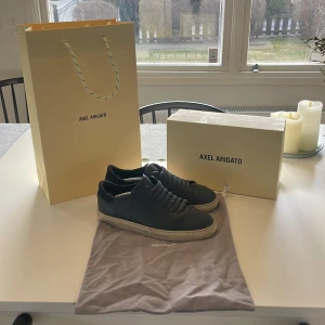 Marinblå läder sneakers från Axel Arigato - Snygga marinblåa läder sneakers från Axel Arigato med vit sula och klassisk snörning. Perfekta för en stilren look. Skorna kommer med originalförpackning och påse. Kom privat vid frågor eller funderingar!😊