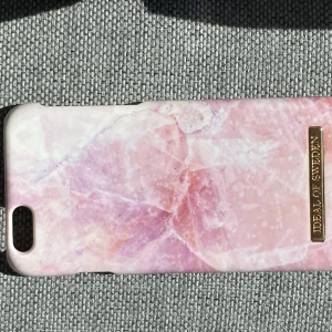Rosa mobilskal från iDeal of Sweden - Snyggt rosa mobilskal från iDeal of Sweden med ett marmorerat mönster. Skalet har en elegant design med en guldig logotypdetalj. Perfekt för att ge din mobil en stilren look. Är inte användt då den är till en iPhone 6 