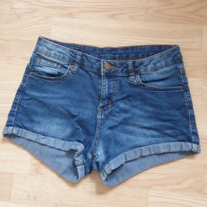 Blå jeansshorts - Snygga mörkare blå lågmidjade jeansshorts med femficksdesign och uppvikta kanter. Perfekta för sommardagar och avslappnade stunder.