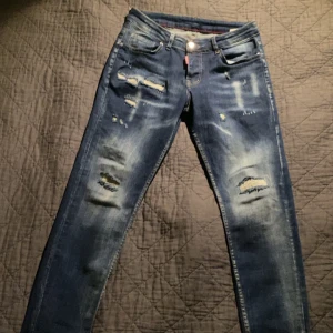 Blå jeans från Dsquared2 - Snygga blå jeans från Dsquared2 med slitna detaljer och en cool, avslappnad look. De har en klassisk femficksdesign och en knappgylf. Perfekta för en trendig stil.