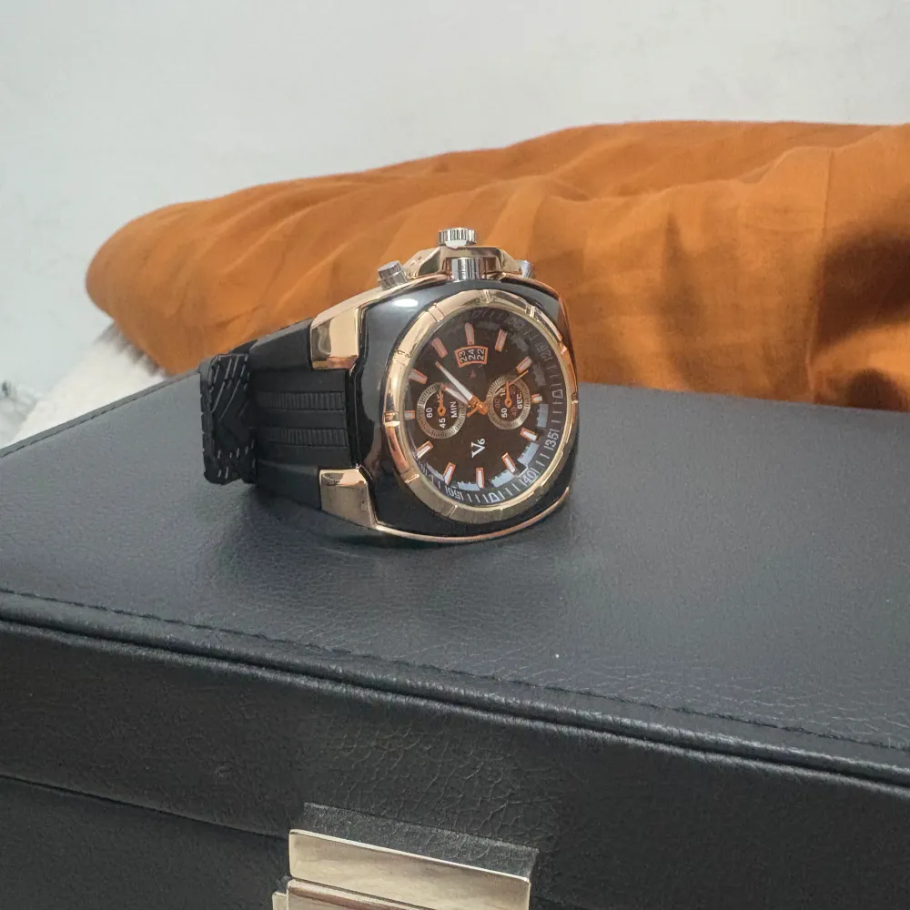 Snygg klocka med svart urtavla och guld detaljer. Den har en robust design med flera funktioner på urtavlan och ett bekvämt svart gummiband. Perfekt för den som gillar en sportig men elegant stil.. Asusteet.