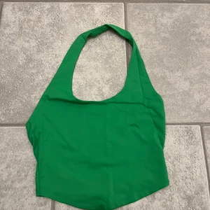 Grön ärmlös linnetopp - Snygg grön ärmlös linnetopp perfekt för sommardagar. Toppen har en enkel design med en rundad halslinje. Perfekt att både klä upp och klä ner