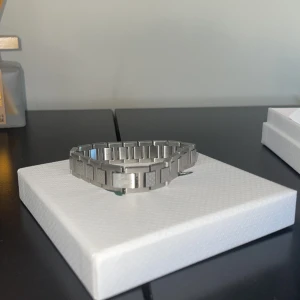 Silverfärgad armbandsklocka från Lacoste - Snygg silverfärgad armbandsklocka från Lacoste med ett stilrent och modernt design. Armbandet har ett geometriskt mönster och kommer i originalförpackning med tillhörande påse. Perfekt accessoar för att komplettera din stil.