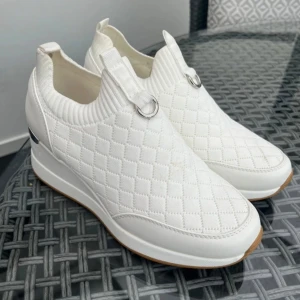 Vita quiltade sneakers i storlek 37 -  River Island - Snygga vita sneakers med quiltad design och kilklack. Skorna har en rund tå och elastisk öppning för enkel påtagning. Dekorativa metallringar framtill och en silverdetalj på hälen ger en modern touch. Endast använd en gång! Se sista bilden för liten fläck på skorna