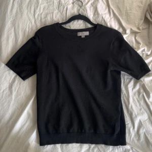 Stickad kortärmad tröja - Säljer en stilren svart kortärmad tröja med rund halsringning. Perfekt för en minimalistisk look. Passar bra till både jeans och kjol. Fint skick!💗