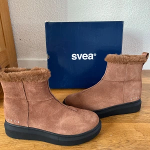 Vinterskor - Snygga bruna mockaboots från Svea med mjukt foder och dragkedja på sidan. De har en robust svart sula och en bekväm passform. Perfekta för kyligare dagar. HELT NYA! Säljer dessa åt min mamma som inte hunnit skicka tillbaka dom när hon insåg att de var för små. NYPRIS 1299. Levereras med original förpackning