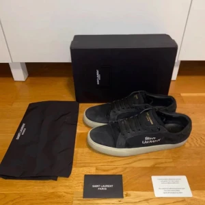 Svarta sneakers från Saint Laurent - Snygga svarta sneakers från Saint Laurent med vit sula och diskret logga på sidan. Skorna är i perfekt skick. Andvända fåtal gånger. 