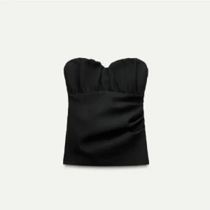 Svart axelbandslös topp - Snygg svart axelbandslös topp med en elegant och stilren design. Perfekt för en kväll ute eller en speciell tillställning. Toppen har en smickrande passform och är lätt att matcha med olika outfits.