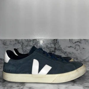 Veja sneakers i blå mocka - Snygga blå sneakers från Veja med vit sula och vita detaljer. Skorna har en klassisk design med snörning och är tillverkade i mocka. Perfekta för en stilren look, men också vardagliga aktiviteter. Använda under kort tid, samt under bra väderförhållanden. Strl 44 men passar upp mot en halv storlek större.  NU 150kr BILLIGARE. 