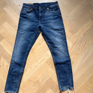 Dondup Jeans - Hej, nu säljer jag ett par blåa Dondup jeans i storlek 32. Jeansen har en liten slitning på höger bakficka men överlag är det ett bra skick på byxorna. Byxorna är i passform slimfit. Hör av dig vid minsta fundering!