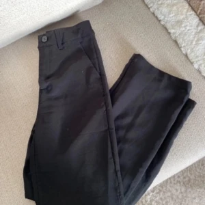 Svarta kostymbyxor - Snygga svarta kostymbyxor med en klassisk design. De har en knapp i midjan och är perfekta för en stilren look. Passar bra till både formella och avslappnade tillfällen.