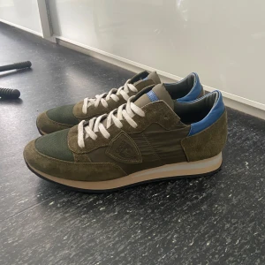 Philippe Model - Gröna Philippe Model med blå detaljer i 9/10 skick. Skorna är i Storlek 42 och om inte priset passar lägg gärna ett bud