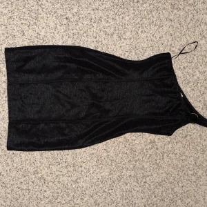 Svart oneshoulder klänning - Snygg svart oneshoulder klänning med en elegant och stilren design. Perfekt för en kväll ute eller en speciell tillställning. Klänningen har en smickrande passform och är tillverkad i ett mjukt material. Har en silver detalj vid ärmen.