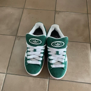  Gröna Adidas Campus  - Snygga gröna sneakers från Adidas med vita detaljer och snörning. Skorna är använda endast en gång och är köpta på NK. Strl 36. Priset kan diskuteras vid snabbt och smidigt köp💗