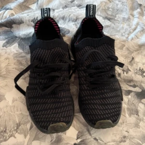 adidas skor - Säljer ett par svarta Adidas nmds i väldigt fint skick. Ett par riktigt sköna skor att ha på sig. Står storleken bak på skon men inget man tänker på när man väl har på sig dom, går säkert att få bort. Går att använda i vardag och som träningsskor. 