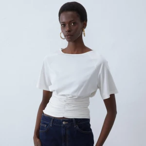 Vit kortärmad topp med rynkdetalj - Säljer denna as snygg vita toppen med korta ärmar och rynkdetalj i midjan, endast testad en gång. Köpt i storlek 3XL men sitter med som en XL/L