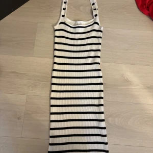 Randig ribbad klänning från Stradivarius - Säljer en snygg vit och svart randig klänning från Stradivarius. Klänningen är ribbad och har en ärmlös design med en tight passform. Är i storlek L men passar mig som har M/S.