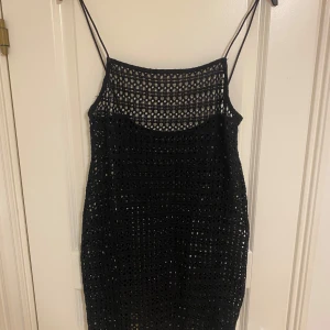Svart virkad kortklänning H&M XS - Svart virkad kortklänning från H&M med tunna axelband och genombrutet mönster. Perfekt för lager-på-lager eller över badkläder. Snygg och trendig modell som ger en cool och avslappnad vibe.