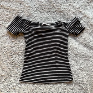 Randig offshoulder topp Pull&Bear - Svart och vit randig offshoulder topp från Pull&Bear.  Top med korta ärmar och tight passform.