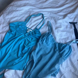Två blå linnetoppar med smala axelband - Säljer två snygga blå linnetoppar från H&M. Ena toppen är i klarblått med v-ringning och smala axelband, den andra är ljusblå och har meshdetaljer samt rynk vid bysten. Perfekta för sommarens alla tillfällen!